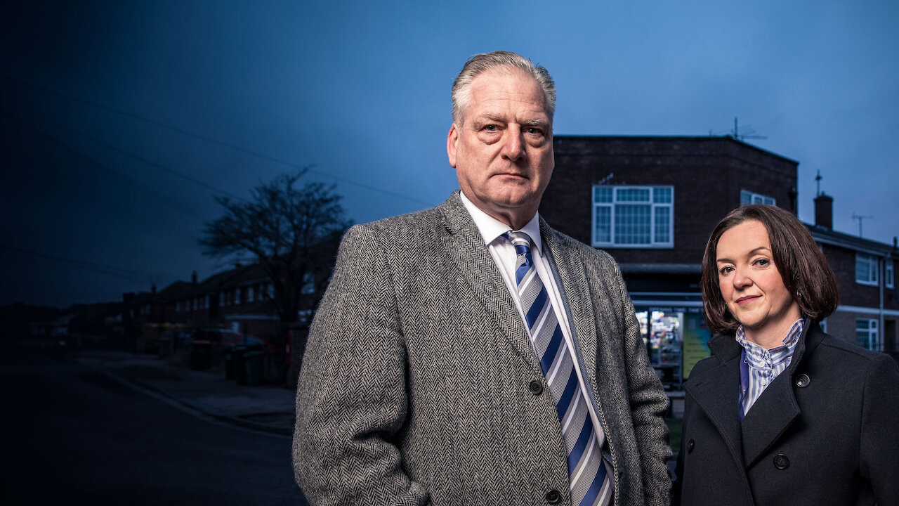 Two detectives from The Real Unforgotten stand on a residential street at dusk