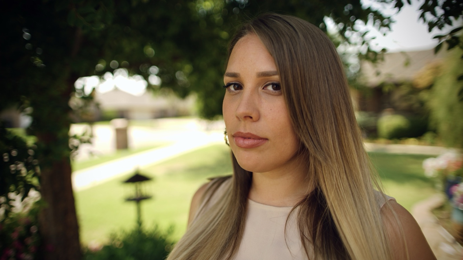 A young woman looks past the camera in a sunlit park